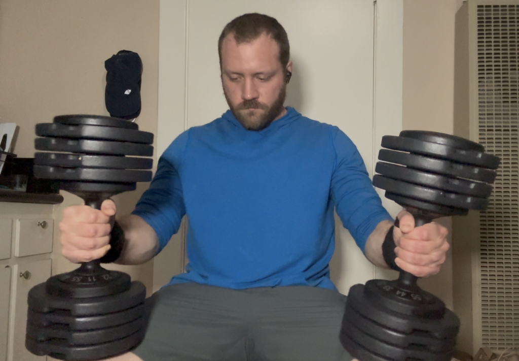 Sitting and holding one Flybird adjustable dumbbell resting on each thigh